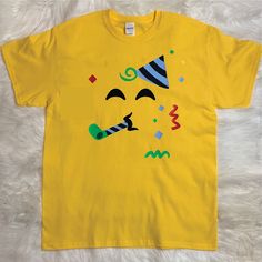 a yellow t - shirt with a face drawn on the chest and a party hat