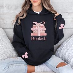 This coquette style bookish hoodie sweatshirt is sure to please the book lover in your family!  It features a stack of books tied with a ribbon and pink bows on the sleeves. This is the perfect gift for a reader, teacher, librarian, mom, grandma, sister, wife, and book lover.   Bookish gift for her birthday, Christmas, or any special occasion.  Thank you for supporting my small business!  Please contact me with questions or comments.  I am here to help!  This design comes in other products. For Cute Cotton Hoodie For School, Fall School Hoodie With Letter Print, Pink Fall Hoodie For School, Pink Hoodie For School In Fall, Bookish Cotton Sweatshirt For Winter, Winter Bookish Cotton Sweatshirt, Winter Cotton Sweatshirt, Bookish Hoodie, Shirt Coquette