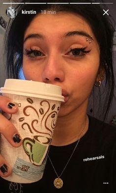 a woman drinking from a coffee cup with her nose covered in black and white designs