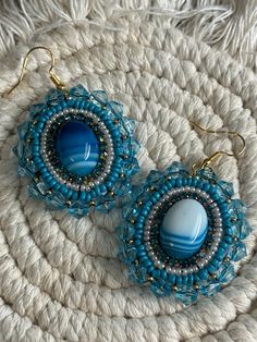 Hand made blue , pearl,  rhinestone and gold beaded dangle earrings with  blue (dyed)  agate stone center. Sewn using nylon black thread. Faux leather backing. Earring hook is hypoallergenic steel. Note: small burn mark from using a flame to clean up extra thread. These were hand crafted by me. All stones and seed beads are not uniform, which gives the overall product a more authentic and "natural" touch. <3 Bead Embroidered Bracelet, Dyed Agate, Blue Beaded Earrings, Embroidered Bracelet, Burn Mark, Blue Dye, Handmade Earrings Beaded, Earring Hook, Le Crochet