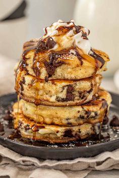 stack of chocolate chip pancakes with syrup drizzled over them on a black plate