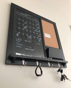 a bulletin board mounted to the wall with keys hanging from it's hooks,