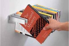 a person holding a stack of books in front of a book holder that holds several books