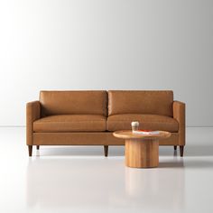 a brown leather couch sitting next to a wooden table on top of a white floor