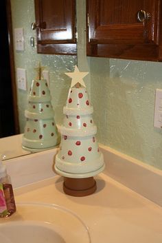 a bathroom sink with a christmas tree on the counter and two small trees sitting on top of it