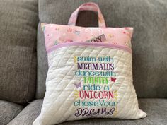 a pillow that is sitting on top of a couch with the words mermaids and unicorns written on it