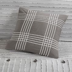 a gray and white pillow sitting on top of a bed