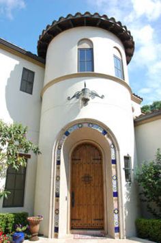 a large white building with a wooden door and arched window on the front entrance to it