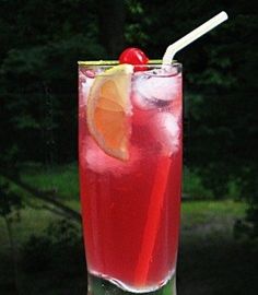 a tall glass filled with red liquid and garnished with an orange slice