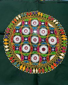 an intricately designed piece of art is displayed on a green cloth with white and red designs