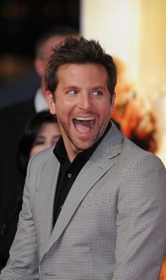 a man in a gray suit and black shirt is making a funny face at the camera