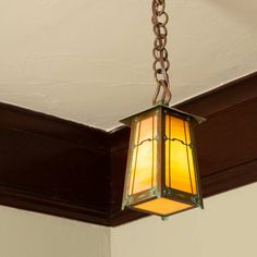 a light fixture hanging from the ceiling in a room with white walls and wood trimmings