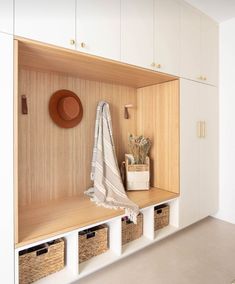 a coat rack with baskets and a hat on it next to a white cupboard filled with items