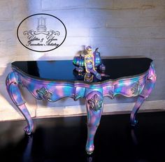 a glass table with an ornate design on the top and legs, painted in multicolors