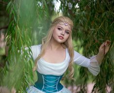 a woman dressed in a blue and white dress is posing for a photo under a tree