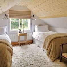 there are two beds in the attic with white blankets on them and one is made up