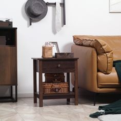 a brown leather couch sitting next to a wooden table with two drawers on top of it