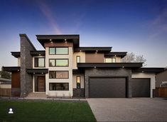 a large house with lots of windows and lights on it's front door, in the evening