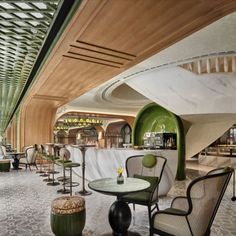 the interior of a restaurant with tables, chairs and stools in front of a spiral staircase