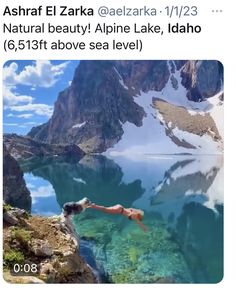 a man diving into the water with mountains in the background