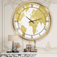 a large gold and white clock with the world on it's face in front of a wall