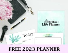 a desk with pink flowers, pen and planner on it