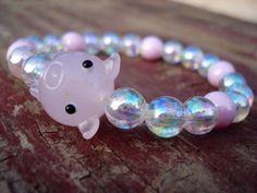 "\"Carnival Pig\" 24x14 Glass Pig Bead 8mm iridescent and pink glass beads Spiritual Meaning of: Opal Color - glory, heavenly, favor, manifold pink- is feminine and romantic, affectionate and intimate, thoughtful and caring. Pig - moves swiftly and with determination. It intuitively knows the best reaction to various situations. STANDARD SIZE FOR MEN IS 8\" AND FOR WOMEN 7\" PLEASE NOTE.... IF YOU DO NOT KNOW YOUR WRIST SIZE, SIMPLY PUT A PIECE OF STRING AROUND YOUR WRIST (in between your wrist Pink Round Beads Kawaii Jewelry, Novelty Pink Jewelry With Round Beads, Novelty Pink Beaded Jewelry, Pink Novelty Beaded Jewelry, Pink Beaded Novelty Jewelry, Whimsical Adjustable Iridescent Jewelry, Kawaii Round Beads Jewelry Gift, Kawaii Pink Bracelet For Party, Pink Plastic Beaded Bracelets For Party