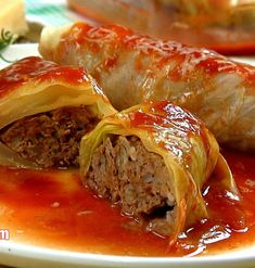 two stuffed cabbage rolls on a plate covered in ketchup and marinara sauce