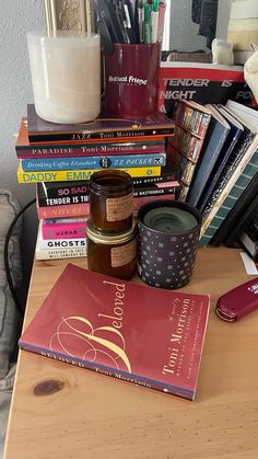 a wooden table topped with lots of books next to a candle and other items on top of it