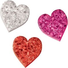 three glitter heart shaped magnets on a white background with one red, one silver and one pink