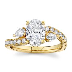 a yellow gold engagement ring with two pear shaped diamonds on the band and side stones