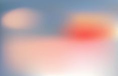 blurry image of an orange and red object in the middle of blue, white, and gray background