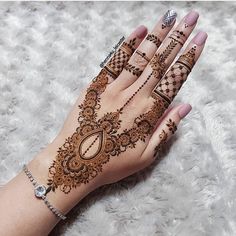 a woman's hand with henna tattoos on it and flowers in the background