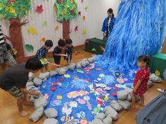 children playing in an indoor play area with blue and green decorations on the walls, while adults watch