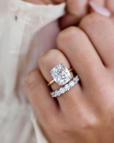 a close up of a person's hand holding an engagement ring