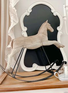 a wooden rocking horse sitting on top of a table next to a cup and saucer