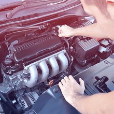 a man working on the engine of a car with his hands in front of it