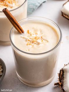 two glasses filled with coconut milk and topped with whipped cream, garnished with cinnamon