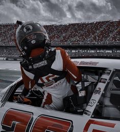 a man sitting in the driver's seat of a race car on a track