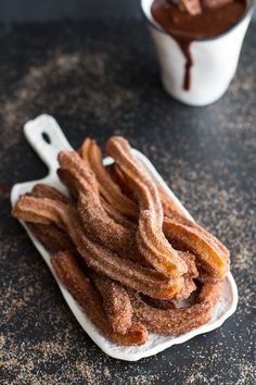 churros sitting on a plate next to two cups of chocolate icecream