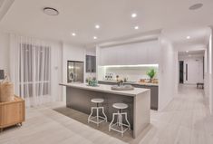 a kitchen with two stools next to an island in the middle of the room