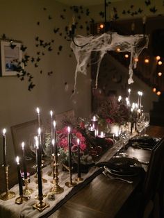 a dining room table is set with candles and flowers in front of a spooky spider net