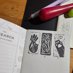 an open book with drawings on it next to a pen and marker, along with other items