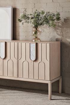 a wooden cabinet with three mirrors on the front and two vases sitting on top