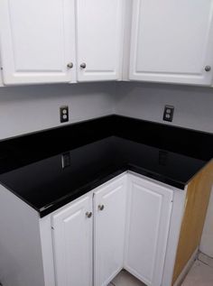 a kitchen with white cabinets and black counter tops