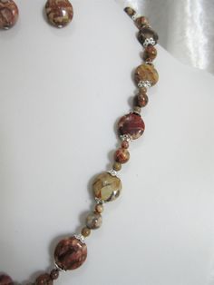 "Birdseye rhyolite jasper is a beautiful, unusual, brown gemstone. Occasional eye-like swirls of brown beige and rust colors run through the stone. The pendant is charming! The necklace is 18\" long with a 3\" silver plated extender. The pendant is a 1.5\" oval. The beads are 4mm rounds, 8mm rounds, and 14mm flat rounds. Silver tone bead caps encase the larger beads. All beads are birdseye rhyolite jasper. The earrings hang 1\" from the loop of the silver plated ear wires. This set will be slipp Earthy Jasper Jewelry With Natural Stones, Earthy Jasper Gemstone Jewelry, Earthy Adjustable Jasper Jewelry, Adjustable Earthy Jasper Jewelry, Earthy Ocean Jasper Jewelry With Natural Stones, Earthy Jasper Gemstone Beads Jewelry, Unique Brown Jasper Jewelry, Brown Jasper For Jewelry Making, Elegant Adjustable Jasper Jewelry