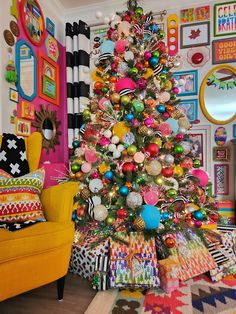 a brightly colored christmas tree in the corner of a room with colorful decorations on it