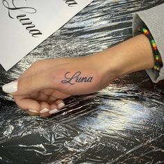 a woman's hand with the word luna tattooed on her left thumb and wrist