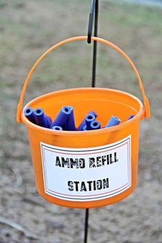 an orange bucket filled with blue plastic eyeballs sitting on top of a metal pole