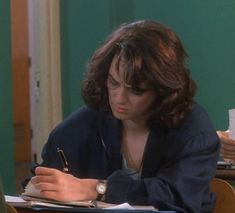 a woman sitting at a desk writing on a piece of paper